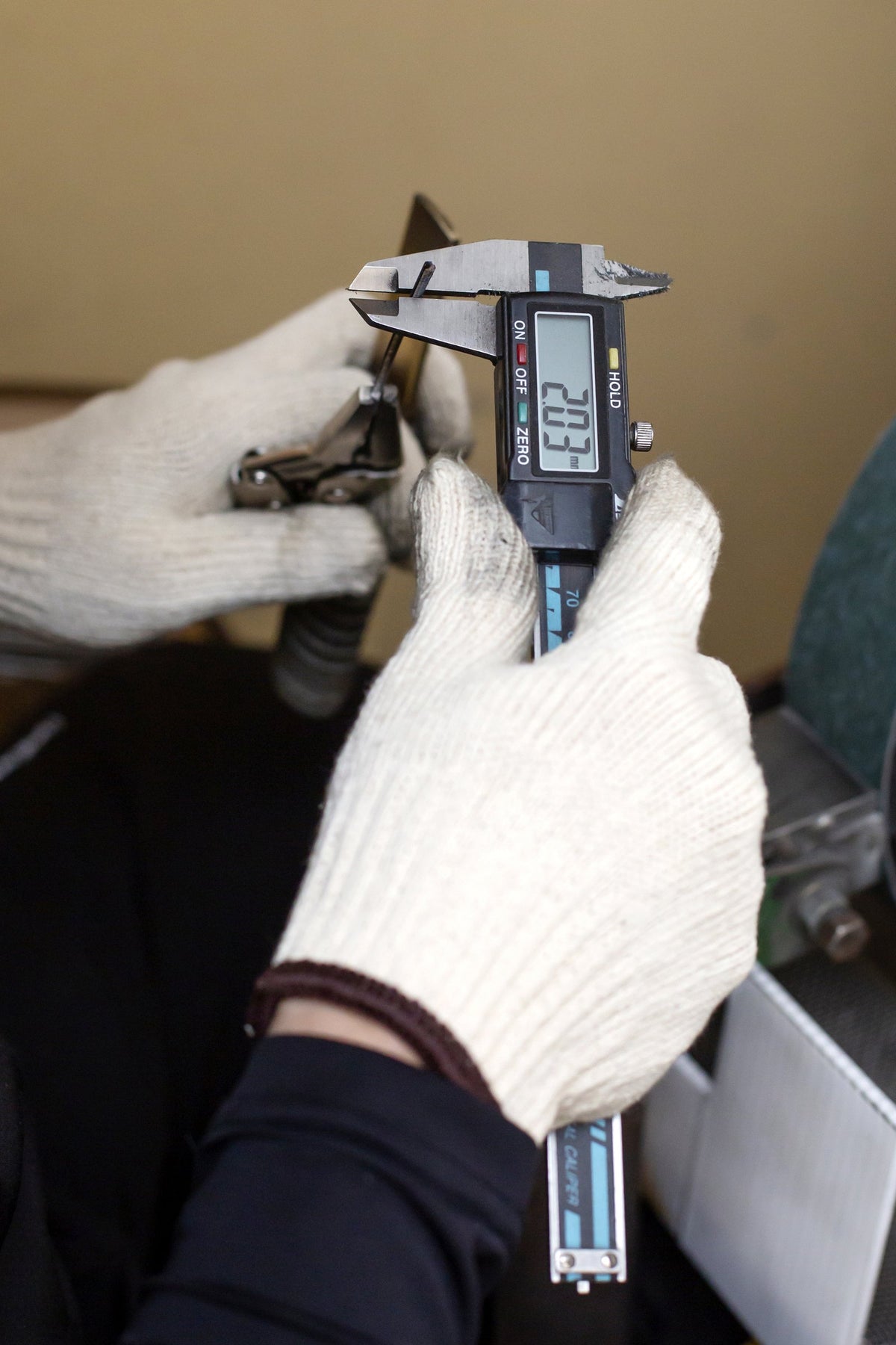 Measuring a blade with a digital caliper during quality control